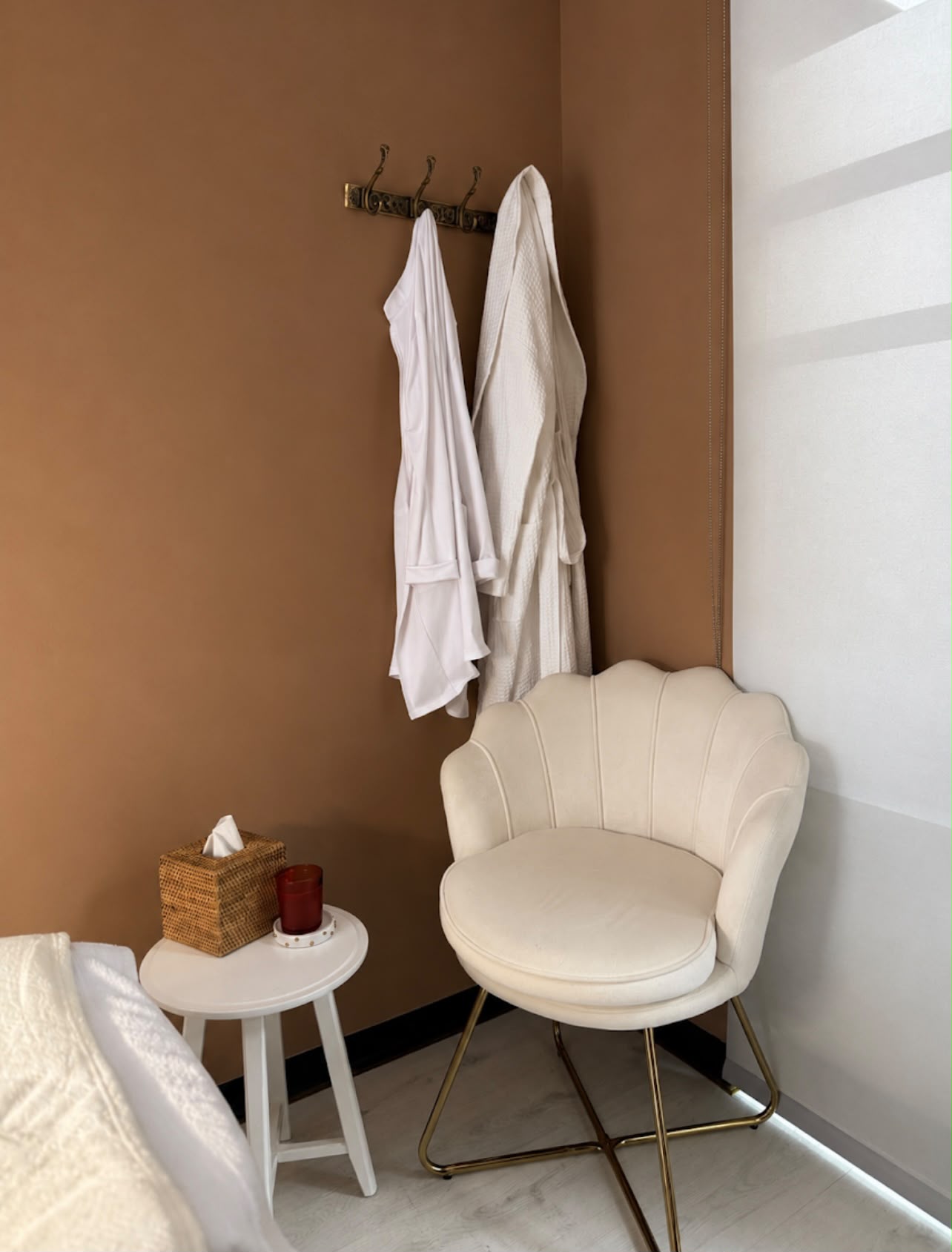 Corner of the treatment room with robes and a velvet chair